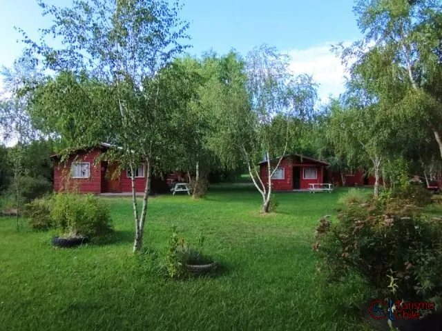 Vista panorámica de cabañas rojas de madera entre árboles en Cabañas Mi Casa