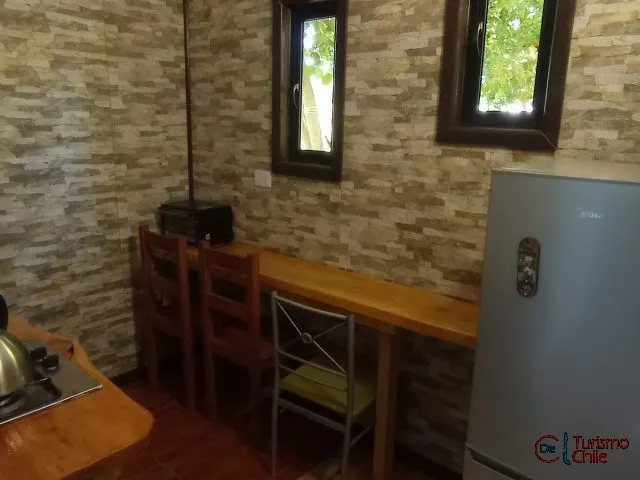 Cocina rústica con mesón de madera, refrigerador y paredes de piedra en Mi Casa