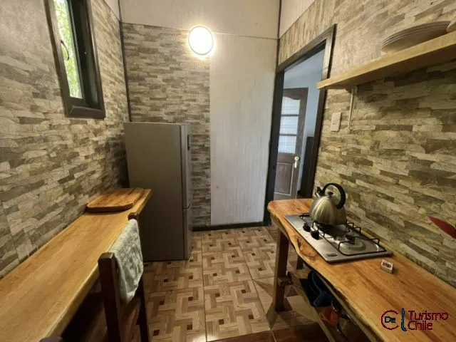 Cocina equipada con cocina a gas, mesones de madera y paredes de piedra