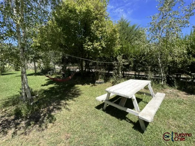 Jardín con mesa de picnic y hamaca roja bajo los árboles en Cabañas Mi Casa