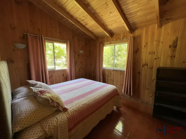 Dormitorio matrimonial con ventanas al jardín y vigas de madera en Mi Casa